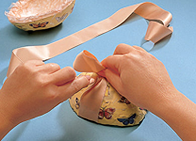 Klistra fast två sidenband på insidorna av den övre ägghalvan och avsluta med att knyta en sidenrosett runt om