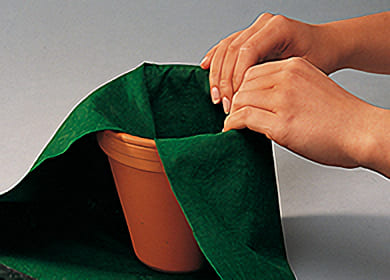 Ställ en lerkruka på en bit grön filt. Vik tyget över krukans kant
