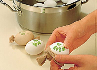 Lägg ett blad på varje ägg. Stoppa äggen i strumpbitarna
